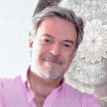 a man in a pink shirt is smiling in front of a plate with a flower design on it