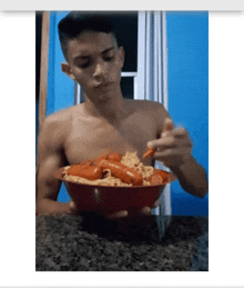 a shirtless man is eating a bowl of spaghetti and sausage