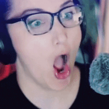a close up of a woman wearing glasses and headphones with her mouth open