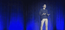 a man stands on a stage giving a presentation