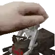 a pixelated image of a person 's hand holding a piece of wood on a table .