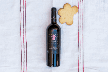 a bottle of wine sits on a cloth next to a cookie