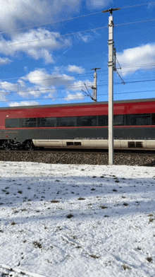 a red and black train is going down the tracks in the snow