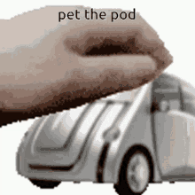 a person 's hand is reaching out to pet a toy car that says pet the pod