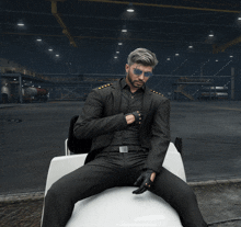 a man in a suit and sunglasses sits on a chair in a warehouse