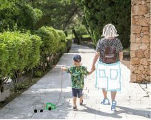 a woman and a child are walking down a path with a drawing of a house in the background