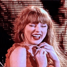 a woman with red hair and bangs is smiling while holding a necklace around her neck .