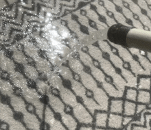 a hose is spraying water on a rug that has a geometric pattern