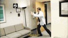 a man in a lab coat is doing a parkour in a hallway .