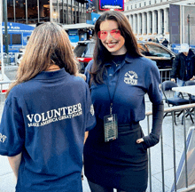 two women wearing volunteer make america great again shirts stand next to each other