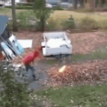 a man in a red shirt is standing next to a trailer with a fire coming out of it .