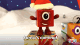 a toy with a santa hat is standing on a box with the words santa 's coming below it