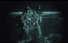 two soldiers are standing in the water at night .