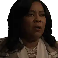 a woman wearing a pearl necklace and a plaid jacket looks surprised