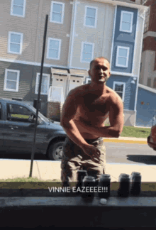 a shirtless man standing in front of a building with the words vinnie eazeeee !!!