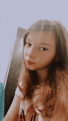 a young girl with long brown hair is wearing a shirt that says " a " on it