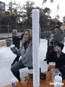 a group of people sitting at a table with a woman holding a cup that says ' texas rangers ' on it