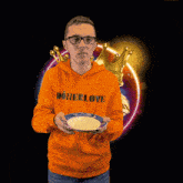 a man wearing an orange donerlove hoodie holds a plate in his hands