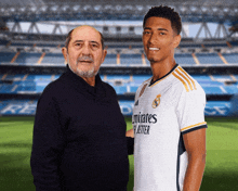 a man stands next to a young man in a white emirates jersey