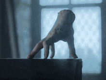 a bloody hand is reaching out from a shelf