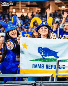 two women holding a flag that says los angeles rams on it