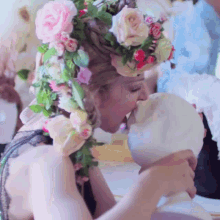 a woman wearing a flower crown kisses a statue