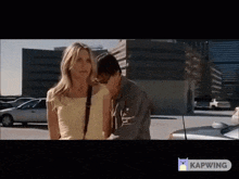 a man and a woman are standing in a parking lot next to a car .