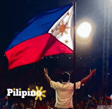 a man stands in front of a crowd holding a flag with the word pilipino on the bottom