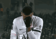 a soccer player is covering his face with his hand while standing on a field .