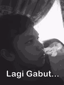 a black and white photo of a man smoking a cigarette and the caption lagi gabut