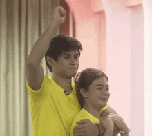 a man in a yellow shirt is giving a woman a piggyback ride