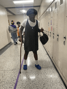 a woman with a cane and a purse walks down a hallway