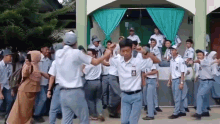 a group of boys in school uniforms are dancing in front of a building with the letter h on it