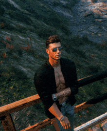 a shirtless man wearing sunglasses and a watch stands on a wooden railing