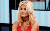 a woman in a red tank top is sitting on a couch .