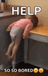 a little girl is laying on top of a wooden desk .