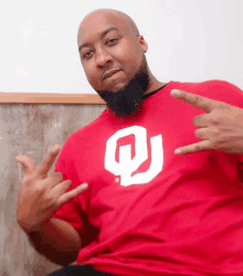 a man wearing a red t-shirt with a white letter o on it