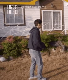 a man is standing in front of a house in a field .