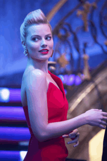 a woman in a red dress is standing in front of a blue staircase