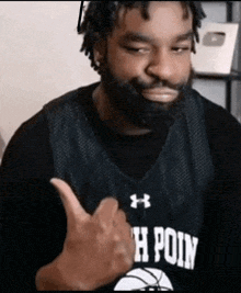 a man with a beard is wearing a basketball jersey and giving a thumbs up