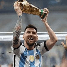 a soccer player is holding a trophy over his head in the air .