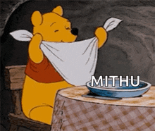 winnie the pooh is sitting at a table with a towel around his neck and the word mithu on the bottom