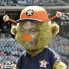 a mascot wearing a hat and a clown nose is standing in a stadium .