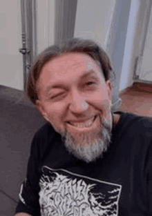 a man with a beard wearing a black shirt is smiling .