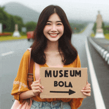 a woman holds up a sign that says museum bola