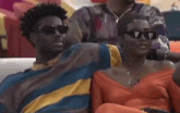 a man and a woman wearing sunglasses are sitting on a couch .
