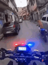 a motorcycle is driving down a street with a car in the background