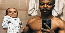 a shirtless man is taking a selfie in a bathroom with a baby in his arms .