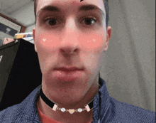 a man wearing a choker with hearts on it looks at the camera