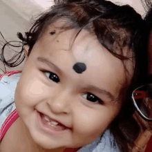 a close up of a baby with a black spot on her forehead .